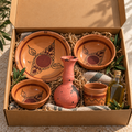 Coffret cadeau NEJMA dans une boîte kraft : assiette plate, assiette creuse, bol, gobelet, bougeoir rouge et huile d’olive